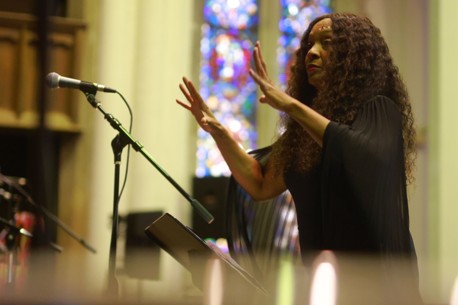 Coco Elysses conducting an AACM ensemble, baton hand lifted as the musicians play